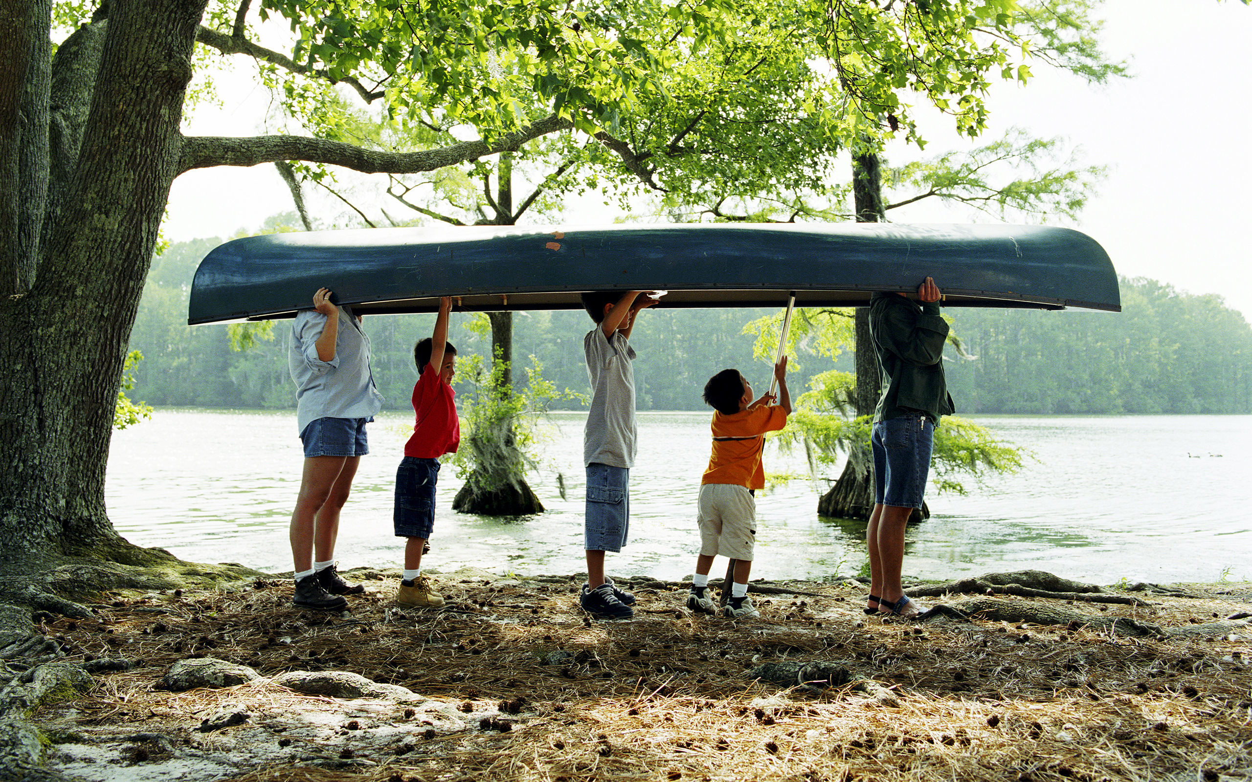 A family carries a canoe near a lake