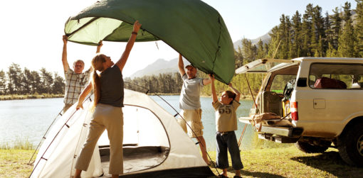 a family works together to pitch a tent