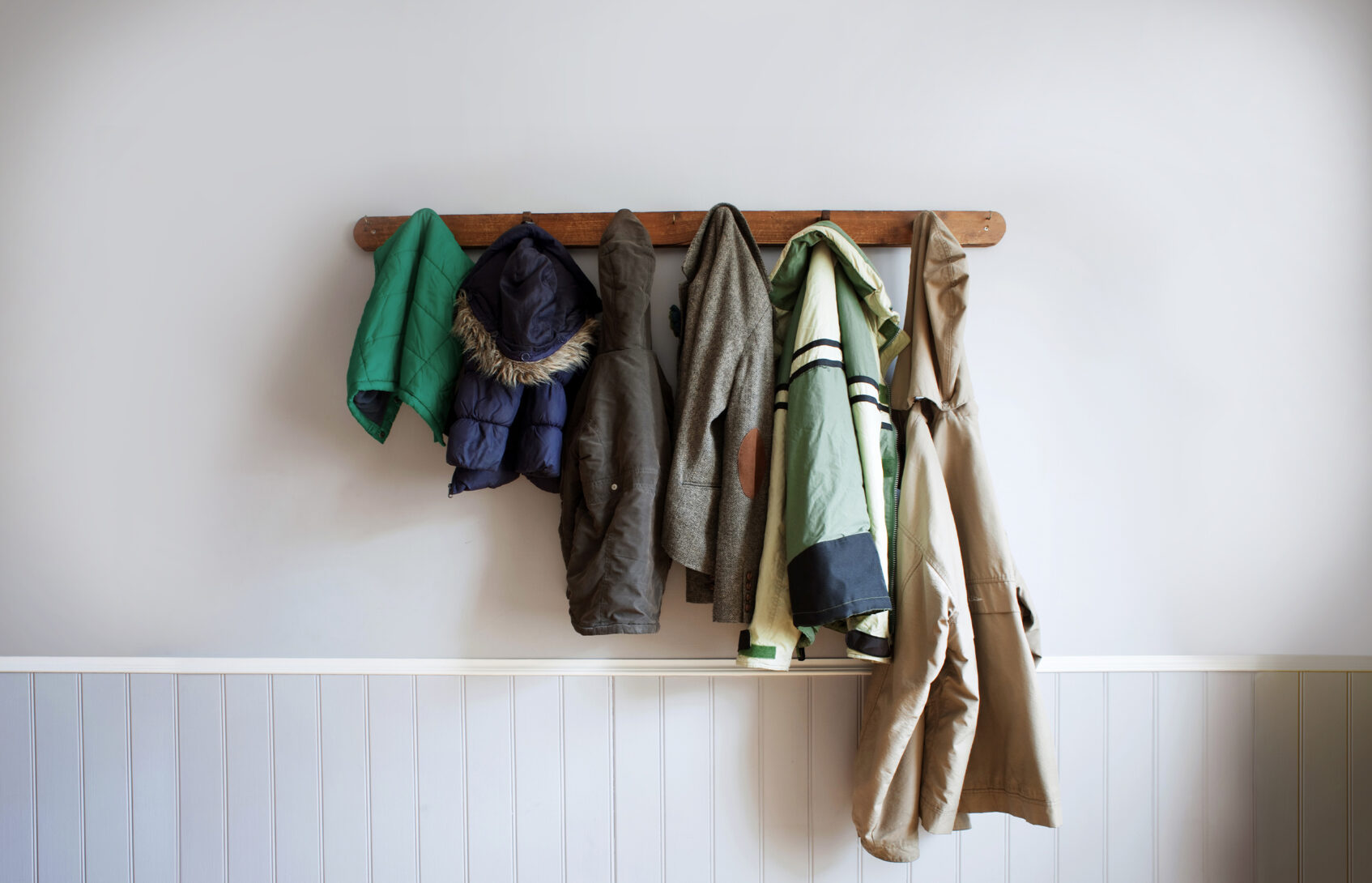 multi-sized child and adult coats hang on a coat rack