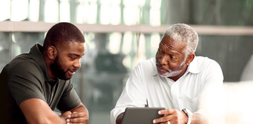 two men, father and son, discuss something they are viewing online